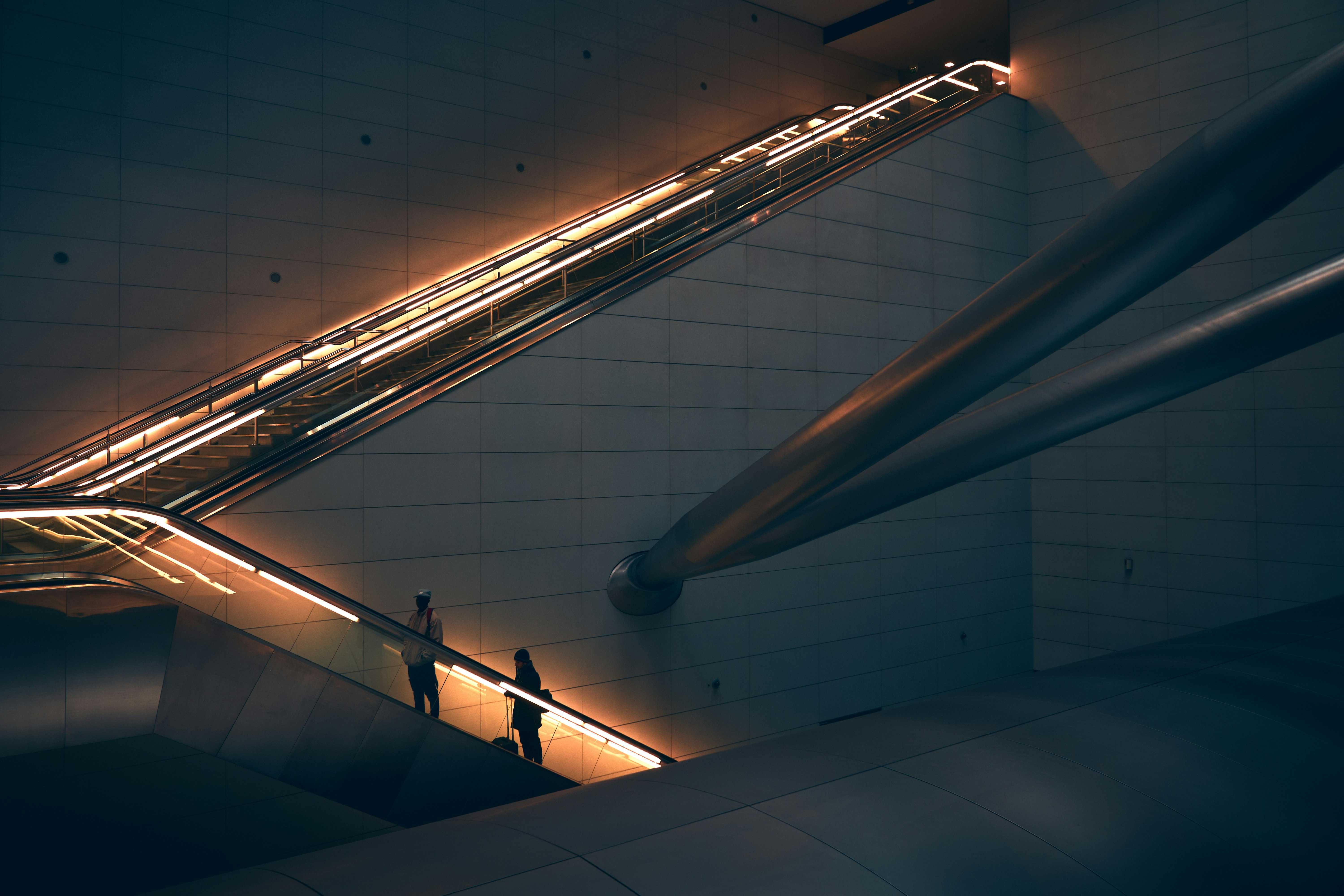 two person standing on escalator